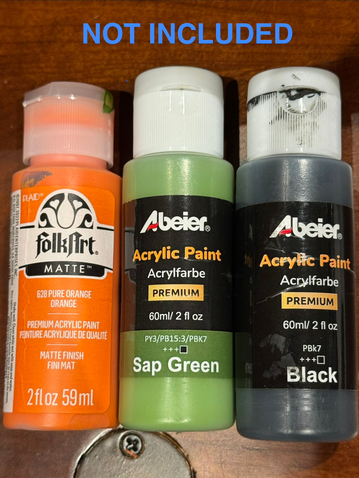 Orange, green, and black acrylic paint shown as supplies that are not included