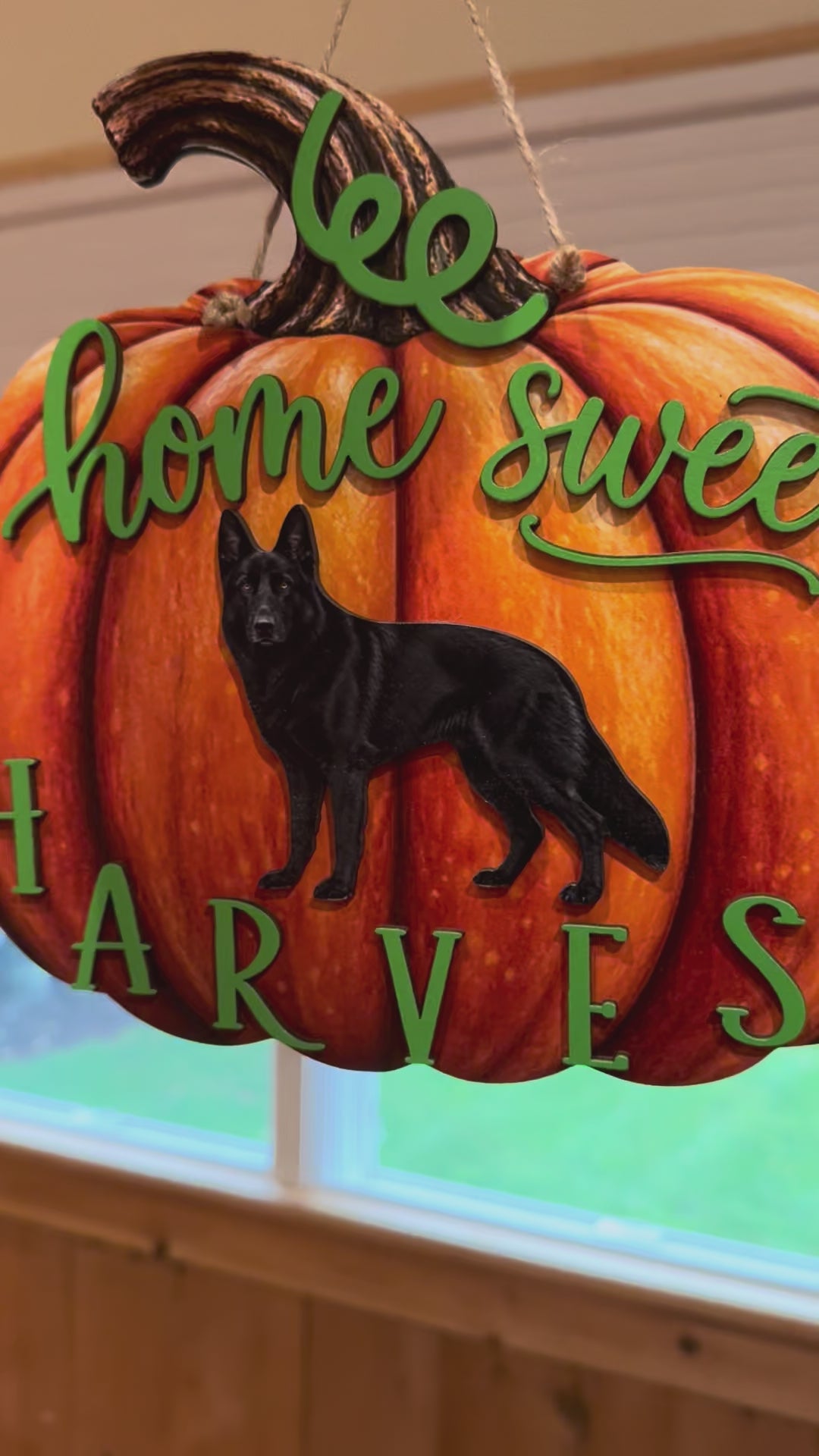 Layered orange pumpkin wood fall sign featuring a black German Shepherd, green lettering, and a hanging cord.